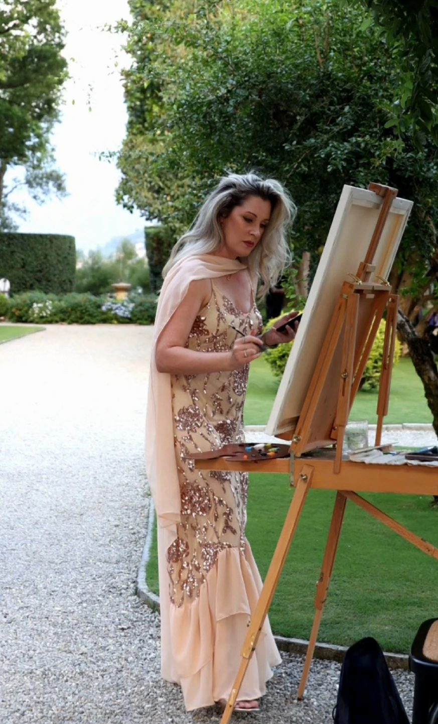 Angela Yfantidou painting at her easel in the gardens of Villa Pizzo during cocktail hour, Lake Como
